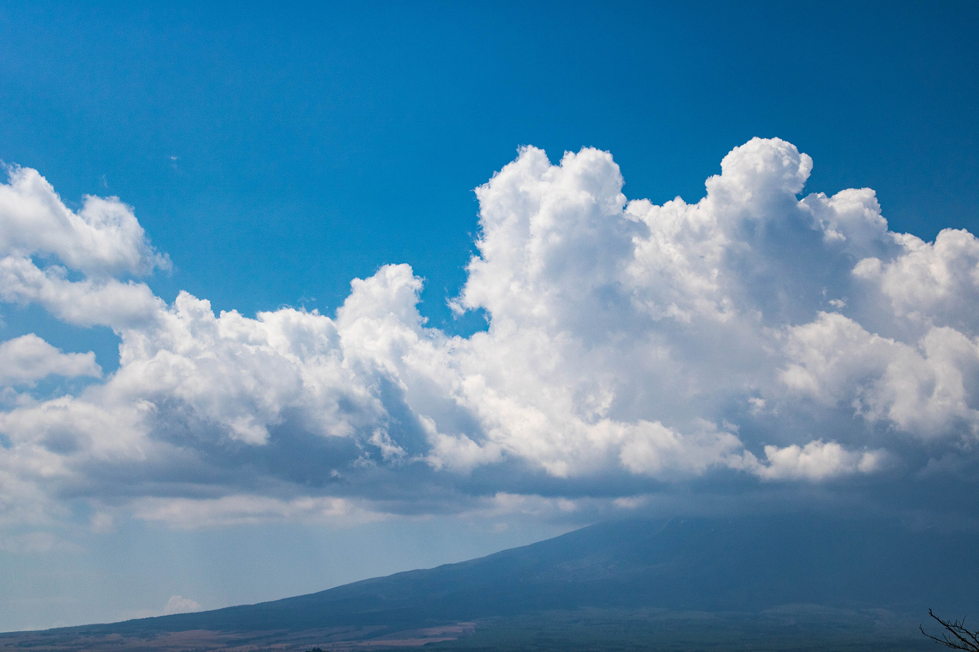 Zoom-in of clouds casting a shadow over the base of a mountain.
